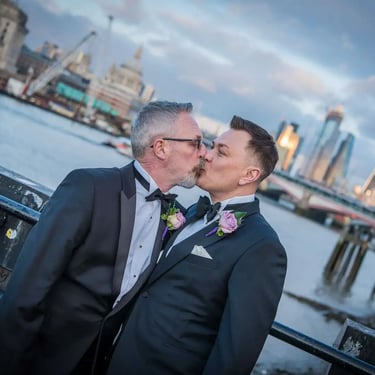 two grooms having a kiss with the city of london in the background