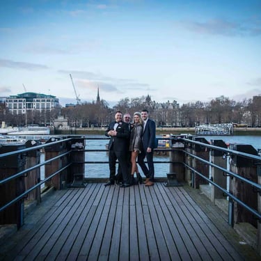 wedding party of four people standing on a pier on the thames London