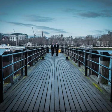 two grooms standing on a southbank london pier over the Thames