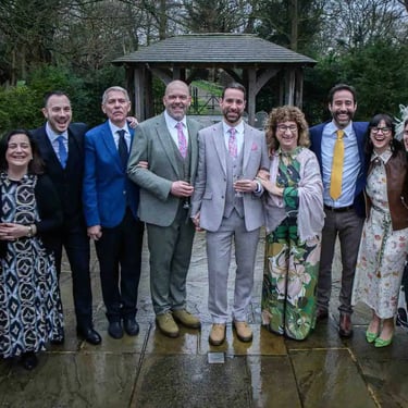 two grooms with family members