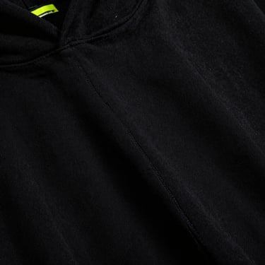 Close-up of a premium black hoodie fabric with thick double-stitched seams, moody lighting