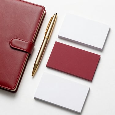 Top-down flat lay of a corporate stationery suite, including embossed leather notebook, gold-accented pen, and heavy-cardstock business cards, clean shadows