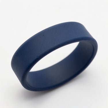 Silicone wristband in navy blue on a white surface, overhead shot, clean studio light, close-up showing texture, no people
