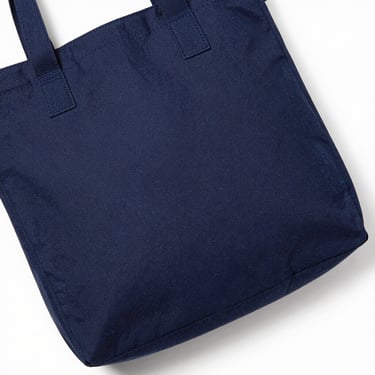 Structured navy canvas tote bag on a white surface, overhead studio shot, sharp detail, no people