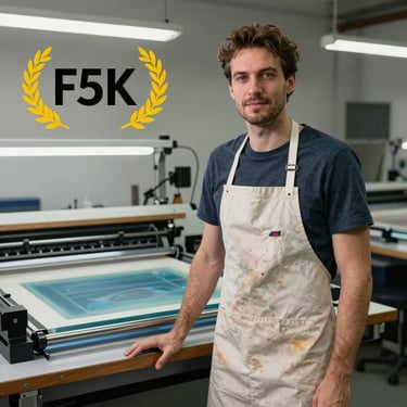 Portrait of a professional screen printer standing next to his workspace, wearing an apron with subtle paint stains.