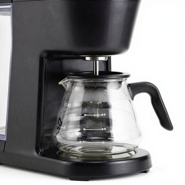 Modern drip coffee maker with a glass carafe, high-key studio lighting, clean white background