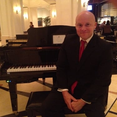 Mark Bulmer Performing On Piano In A Suit
