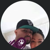 A circular profile photo of a couple posing closely together while the man wears a black and green baseball cap.