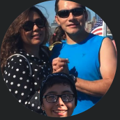 A happy family of three wearing sunglasses and smiling outdoors on a sunny day.
