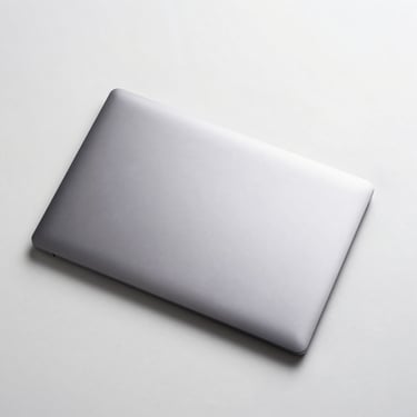 Overhead flat-lay of a 14-inch laptop closed on a clean white surface, neutral studio lighting, aluminium lid visible, no hands or accessories
