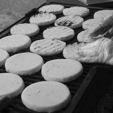 Las manos de la vendedora de arepas de maíz guardan el calor del fogón