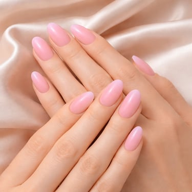 Elegant almond-shaped pink gel manicure on hands resting over soft silk fabric.