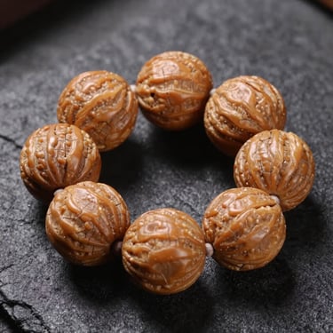 Symmetrical close-up of a five-mukhi Rudraksha bead, showing clean natural fissures, resting on textured charcoal surface