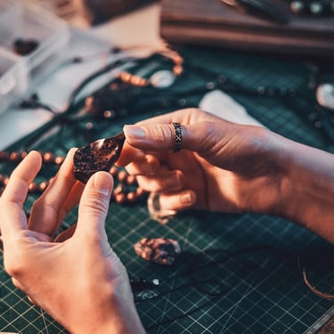 Manos de artesana elaborando joya de macramé con piedra natural de México