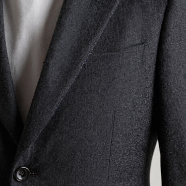 Close-up of a dark grey structured Reserva blazer lapel, showing precise stitching and premium wool blend texture.