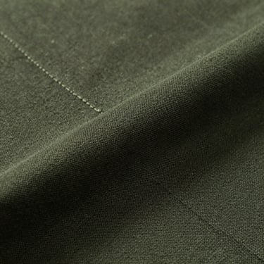 Macro shot of dark olive Reserva chino cotton fabric, showcasing the fine diagonal weave and structured seams.