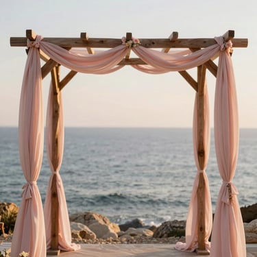 A refined outdoor wedding ceremony setup overlooking the sea, delicate pastel pink fabrics draping a wooden arch, soft coastal light