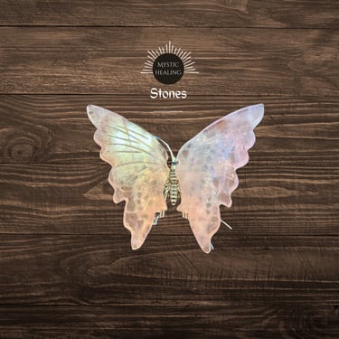 Iridescent rose quartz butterfly carving for healing crystals collection on a dark wood background.