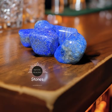 Polished blue lapis lazuli crystals and healing stones displayed on a wooden surface.