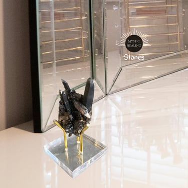 Smoky quartz crystal cluster on a gold metal stand for home decor and spiritual healing.