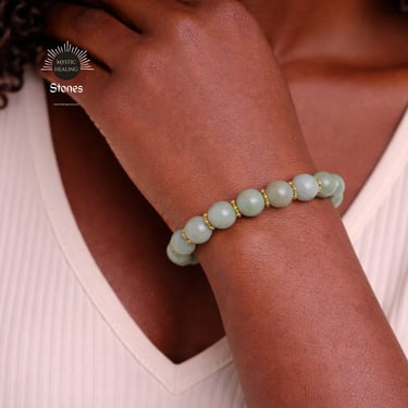 A person wearing a jade crystal bead bracelet with gold accents for healing.