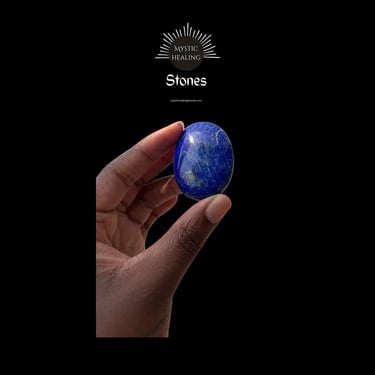 A hand holding a polished blue lapis lazuli healing stone against a black background.