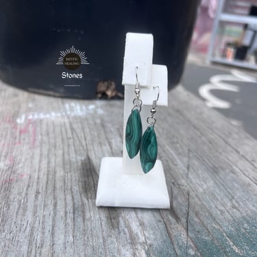 Green malachite crystal leaf earrings displayed on a white jewelry stand.