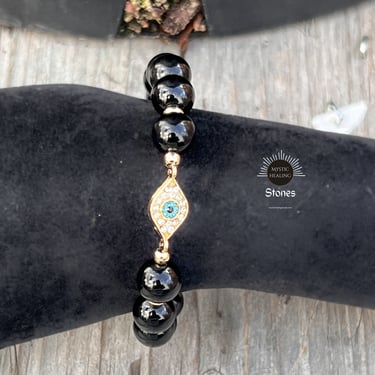 Obsidian beaded bracelet featuring a gold evil eye charm with turquoise and crystals.