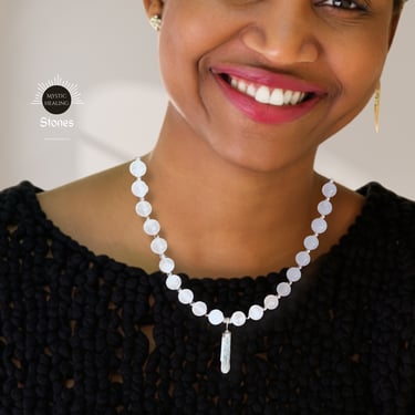 Smiling woman wearing a pink calcite bead necklace with a crystal pendant.