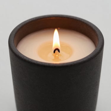 Dark charcoal ceramic candle vessel, burning cleanly with a bright golden flame.
