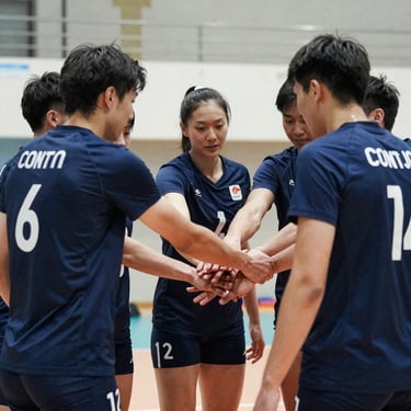 An unposed team huddle of volleyball players in matching navy jerseys, hands joined in the center, bright gym lighting, capturing a moment of genuine community and sportsmanship.
