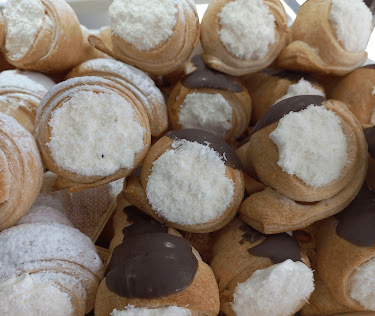 Servicio de conitos de hojaldre y crema chantilly presentados en un plato blanco para evento o merie