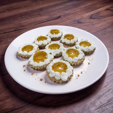 Mini tartas de frutas con glaseado de crema batida y glaseado de albaricoque en un plato blanco sobr