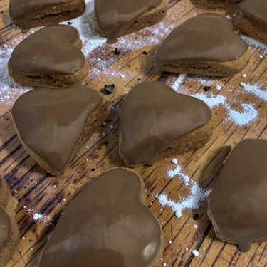 Galletas de jengibre en forma de corazón con glaseado de chocolate suave sobre una tabla de madera c