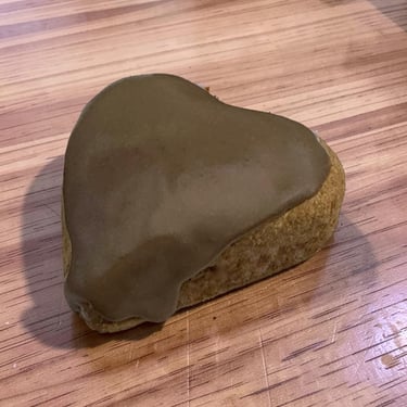 Una galleta de mantequilla en forma de corazón con glaseado de chocolate suave sobre una mesa de mad