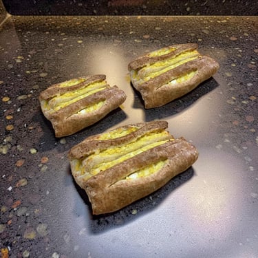 Three freshly baked Finnish karelian pastries with egg butter on a dark stone countertop.