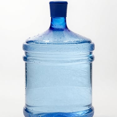 A pristine blue 5-gallon water jug with condensation beads, bright high-key lighting, crisp focus.