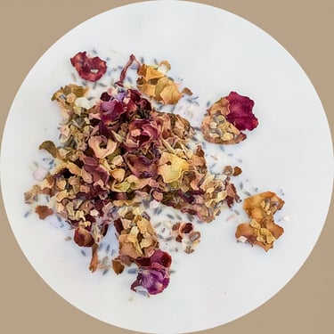 Circular image showing dried lavender buds and flower petals scattered on a white surface.