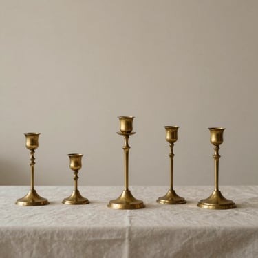 Minimalist portrait of an artisan arranging brass candlesticks on a long reception table, soft diffused light