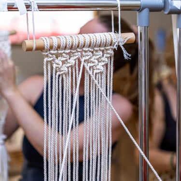 Mujer tejiendo macramé en un taller.