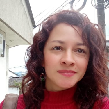 Una mujer con cabello ondulado color castaño rojizo, usando un suéter rojo de cuello alto y aretes .