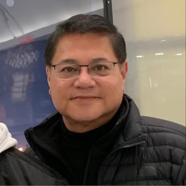Professional man wearing glasses and a black puffer jacket in a indoor setting.