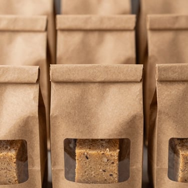 Straight-on close up of clean, structured paper box packaging for artisanal edibles, minimal design, natural daylight, soft shadows
