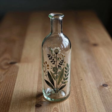 Artisan glass bottle with a hand-labeled botanical design on a raw timber surface, natural shadows