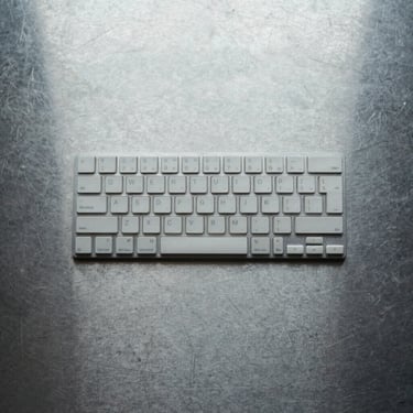 Top-down flat lay of physical keys on a clean steel surface, cool overcast daylight, sharp shadows, high contrast.