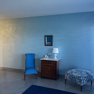 Chambre aux murs bleu patiné avec mobilier classique et assises assorties.