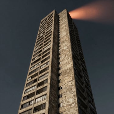 Dramatic low-angle shot of a brutalist concrete tower in São Paulo under a dark sky, illuminated by a single warm copper beam.