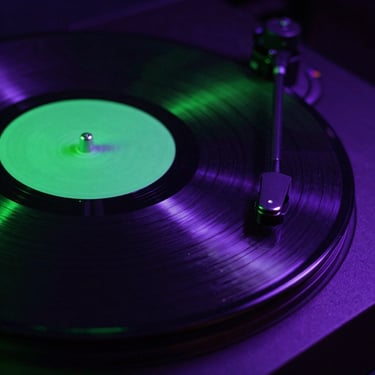 Macro shot of spinning vinyl under neon green strobe lights, dynamic Dutch angle.
