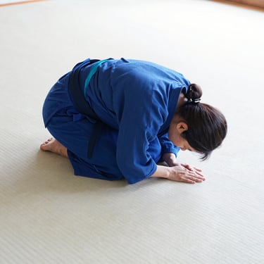 Close-up of respectful bowing on a clean white tatami, bright natural dojo light, minimalist composition, 35mm