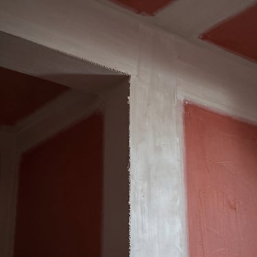 Crisp drywall mudding lines on a newly taped wall joint, smooth plaster texture under dramatic raking light